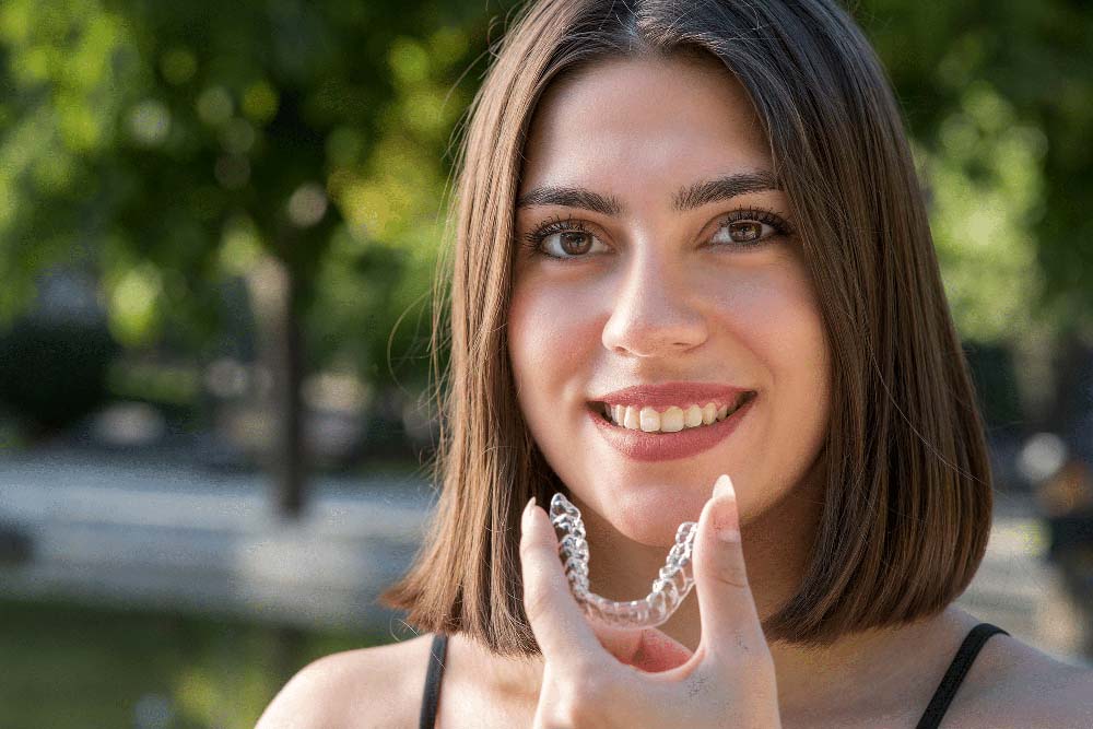 Young woman holding Invisalign clear aligners at Griffith Dental