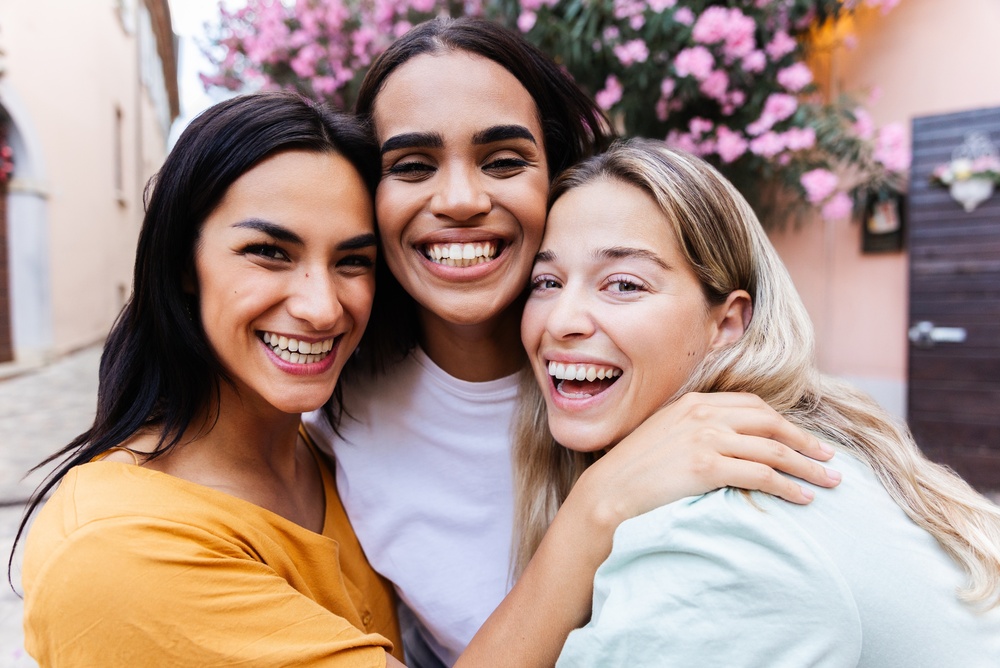 Happy friends showing healthy smiles at Griffith Dental after they Refer a friend